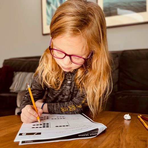 Monica's daughter doing her math homework at the coffee table